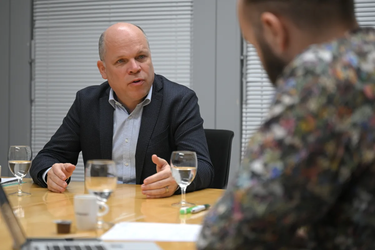 Ein Mann beantwortet an einem Tisch Fragen.